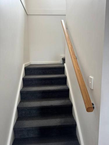 a staircase in a building with a wooden rail at Sandcastle - A Esplanade Place, Stunning Views in Kingscote