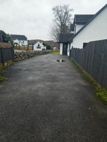 an empty driveway with a fence and a house at Beolary in Oban