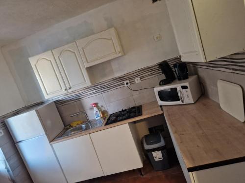 une petite cuisine avec des armoires blanches et un micro-ondes dans l'établissement Une maison avec 3 chambres, à Bédarrides