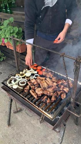 a man cooking meat and vegetables on a grill at Mirador de Miranda, Apartamentos Rural & Spa Inc in Cutiellos