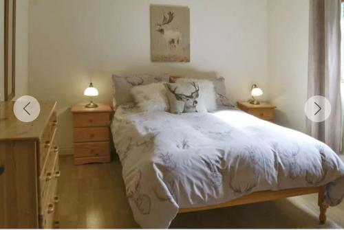 a bedroom with a white bed with two lamps and a dresser at Rowan Cottage, NC500 in Greenland