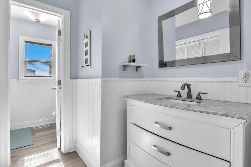 a white bathroom with a sink and a mirror at SeaSide by Oak Island Accommodations in Oak Island