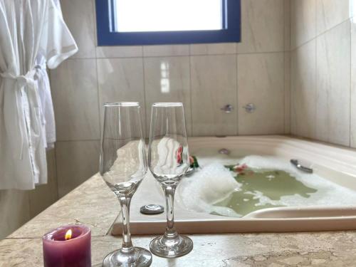 duas taças de vinho sobre um balcão ao lado de uma banheira em Pouso Aconchego - 350m Maria Fumaça em Tiradentes