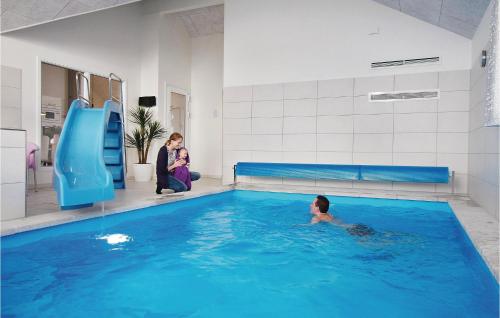a boy in a swimming pool next to a water slide at Awesome Home In Ringkøbing With Sauna in Klegod