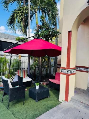 a patio with a red umbrella and chairs on grass at Beds & Sheets little Havana in Miami