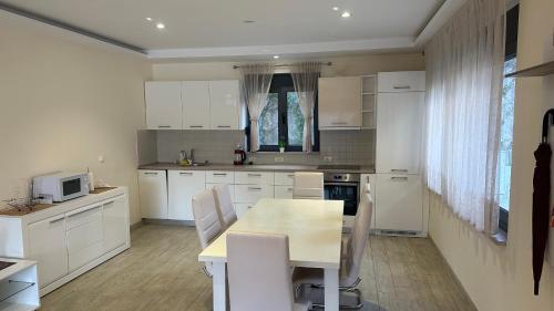 a kitchen with white cabinets and a table and chairs at Drazn vrt in Kotor