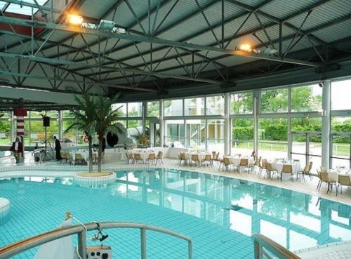 une grande piscine avec des tables et des chaises dans un bâtiment dans l'établissement Maison avec 2 chambres et jardin, à Montfort-le-Gesnois