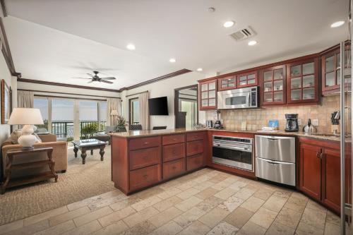a kitchen with wooden cabinets and a living room at Waipouli Beach Resort and Spa Kauai by OUTRIGGER in Kapaa