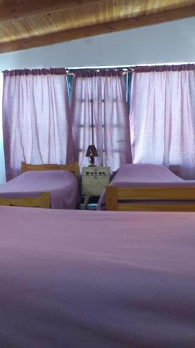 2 camas en un dormitorio con sábanas y cortinas púrpuras en Hospedaje el buen descanso, en Gobernador Gregores