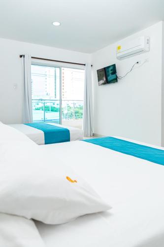 a white bedroom with two beds and a window at Hotel Aguamarina in Santa Marta