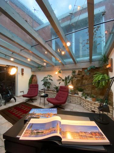 a room with a book on a table with two red chairs at Wunderschönes Ferienhaus mit Fernblick, unweit von Limburg und Rhein-Main-Gebiet in Hünfelden