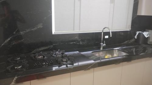 a kitchen counter with a sink and a stove at Quarto com ar e banheiro estacionamento e Wi-Fi in Sinop