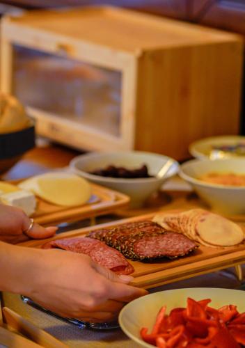 a person making a sandwich on a table with food at Bark Inn - Bed and Breakfast in Braşov