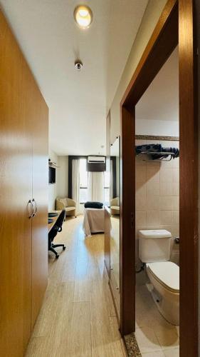 a bathroom with a toilet and a bed in a room at Flat aconchegante 5 andar in Brasília