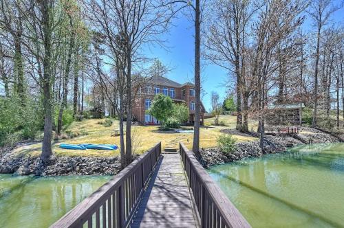 a house with a wooden fence next to a river at Flip Flop Therapy by AvantStay Lakefront Home w Game Room Dock Access in Mooresville