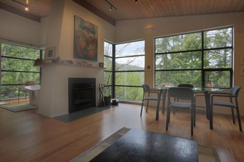 a living room with a table and chairs and a fireplace at Moon Dance Perch in Madeira Park