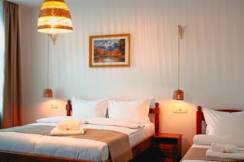 a bedroom with two beds and a picture on the wall at Bark Inn - Bed and Breakfast in Braşov