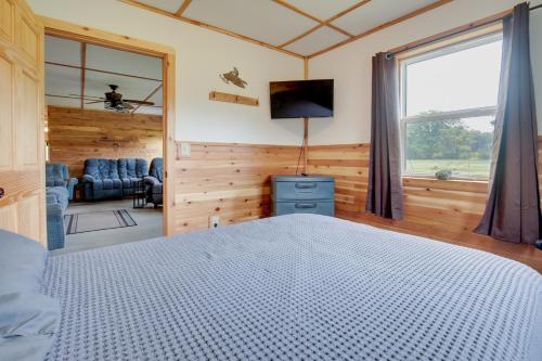 a bedroom with a bed and a tv and a window at Toivola Home with Fire Pit 8 Mi to Lake Superior! in Toivola