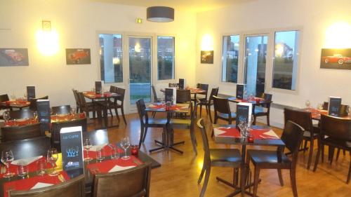 - une salle à manger avec des tables, des chaises et des fenêtres dans l'établissement Logis Cottage Hôtel, à Calais