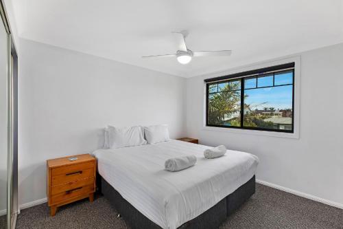 a white bedroom with a bed and a window at North Entrance Beach House in The Entrance