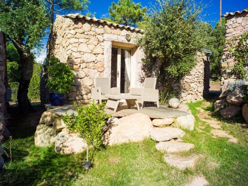 a stone house with a table and chairs in a yard at Hôtel Ambassador Palombaggia in Porto-Vecchio