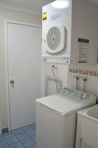 a small kitchen with a white refrigerator and a microwave at Tradewinds Apartment 4 in South West Rocks
