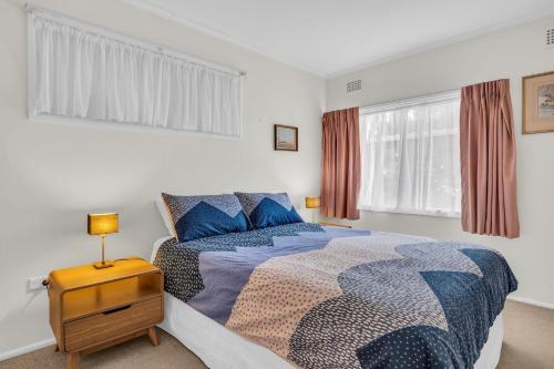 a bedroom with a bed and a table with a lamp at 27 Kanangra Street Pambula Beach in Pambula Beach