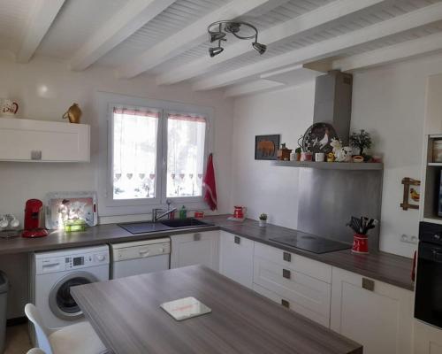 une cuisine avec des armoires blanches et une table en bois dans l'établissement Maison à 5 min des pistes, à La Cabanasse