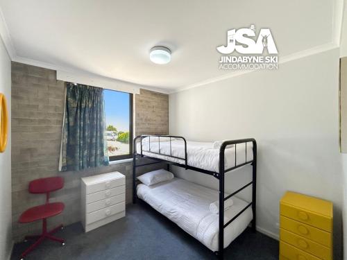 a bedroom with two bunk beds and a chair at Tanderra 4 in Jindabyne