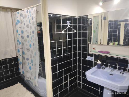 a black tiled bathroom with a sink and a shower at Buenos Aires, CABA in Buenos Aires