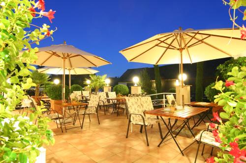 a patio with tables and chairs and umbrellas at Landhotel Bergischer Hof GmbH Marialinden in Overath