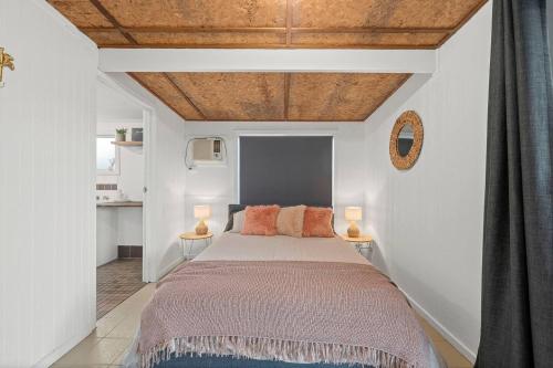 a bedroom with a bed and two tables with lamps at Driftwood Beach House - A Cosy Coastal Cottage in Aldinga Beach