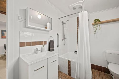 a bathroom with a sink and a toilet and a shower at Driftwood Beach House - A Cosy Coastal Cottage in Aldinga Beach