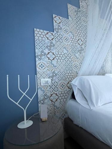 a bedroom with a bed and a table with a lamp at Hotel Melydà in Pozzuoli