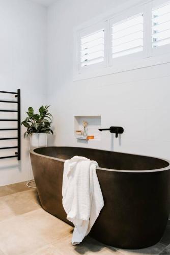 a bath tub with a towel on it in a bathroom at The Wine Manor - Lavish Poolside Living in Mudgee
