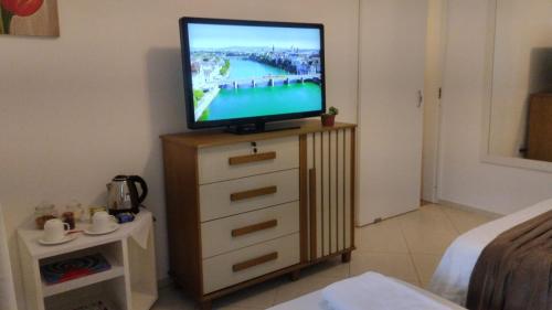 a television sitting on top of a dresser in a room at Suítes Garden in Pomerode