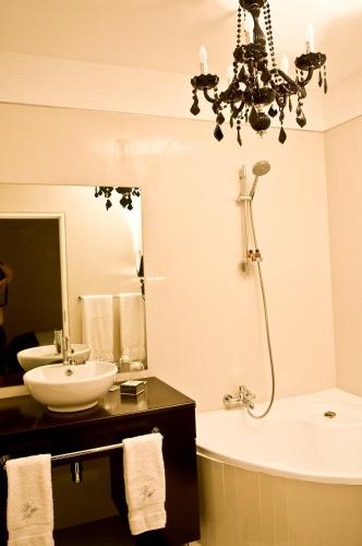 a bathroom with a chandelier and a tub and a sink at Villa Moringa Guesthouse in Windhoek