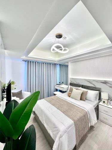 a white bedroom with a large bed and a plant at Azure North Amirah’s Place in San Fernando