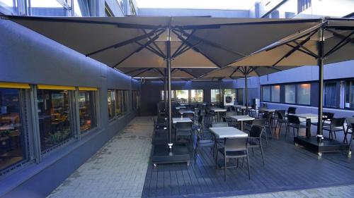 a dining area with tables and chairs and umbrellas at TIBET HOTEL am Airport Düsseldorf-Ratingen in Ratingen