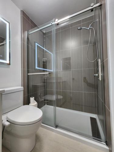 a bathroom with a toilet and a glass shower at 2-bed house for downtown, stampede & mountains in Calgary