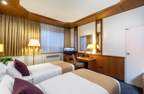 a hotel room with two beds and a desk at Leonardo Hotel Frankfurt City South in Frankfurt/Main