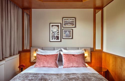 a bedroom with a bed with two red pillows at Leonardo Hotel Frankfurt City South in Frankfurt/Main