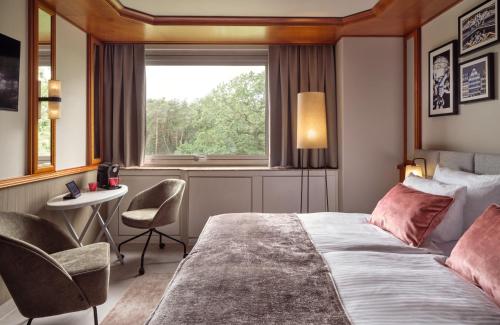 a bedroom with a bed and a desk and a window at Leonardo Hotel Frankfurt City South in Frankfurt/Main