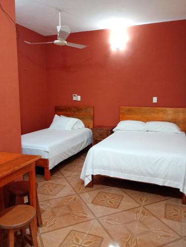 two beds in a room with red walls at Hospedaje casa Yuca in Valladolid