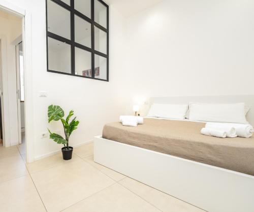 a white bedroom with a large bed and a potted plant at Valguarnera Studio Apartments in Palermo
