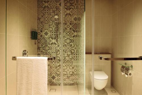 a bathroom with a toilet and a shower with a glass door at Palm Springs Hotel Dili in Dili