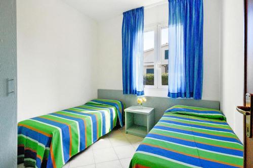 a bedroom with two beds and a window with blue curtains at Villa in Cecina Mare near Sandy Beaches in Marina di Cecina