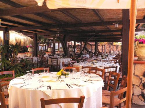 a dining room with white tables and chairs with flowers on them at Hotel Club Torre Capovento in Sperlonga