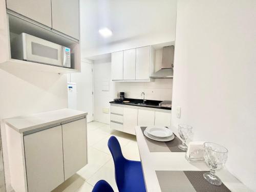 a white kitchen with a table and blue chairs at Flat WiseSP - Expo Anhembi in Sao Paulo