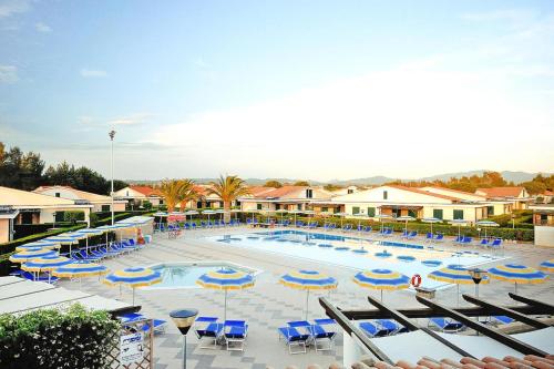 a large swimming pool with blue chairs and umbrellas at Villa in Cecina Mare near Sandy Beaches in Marina di Cecina